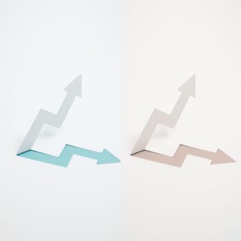 Why Some Months Feel Worse Than Others (Even When Revenue Is Similar) Two images arrow point up and arrow pointing down, look the same except the bottom arrow, the left blue, the right pink. on a gray/ white background.
